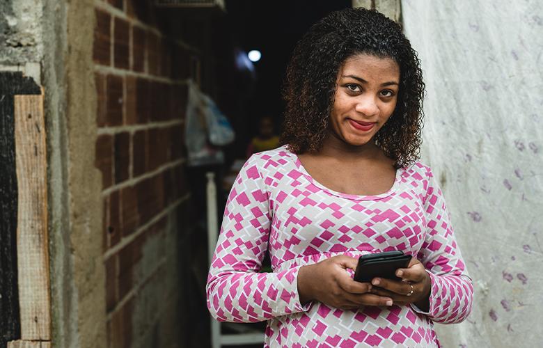 What the Tech: Can WhatsApp Support Program Delivery with Busy Families? A women using a phone representing What the Tech: Can WhatsApp Support Program Delivery with Busy Families?