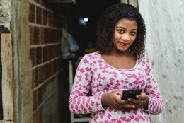 What the Tech: Can WhatsApp Support Program Delivery with Busy Families? A women using a phone representing What the Tech: Can WhatsApp Support Program Delivery with Busy Families?