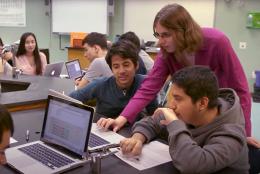 A photo of teacher and students using computers