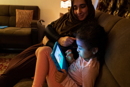 A photo of parent and children using tablet