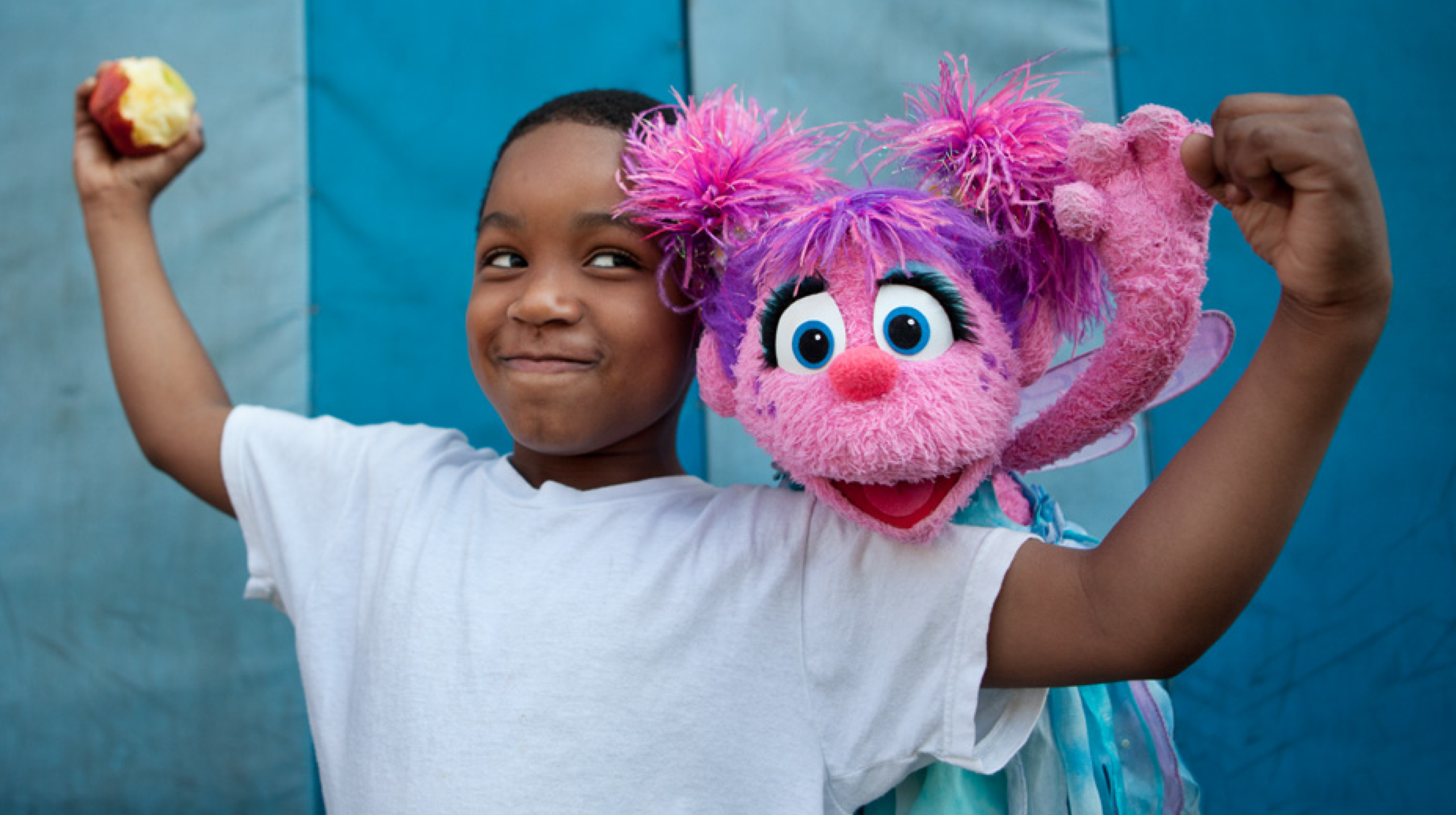 Image of a child posing for a photo with a colorful Muppet character.