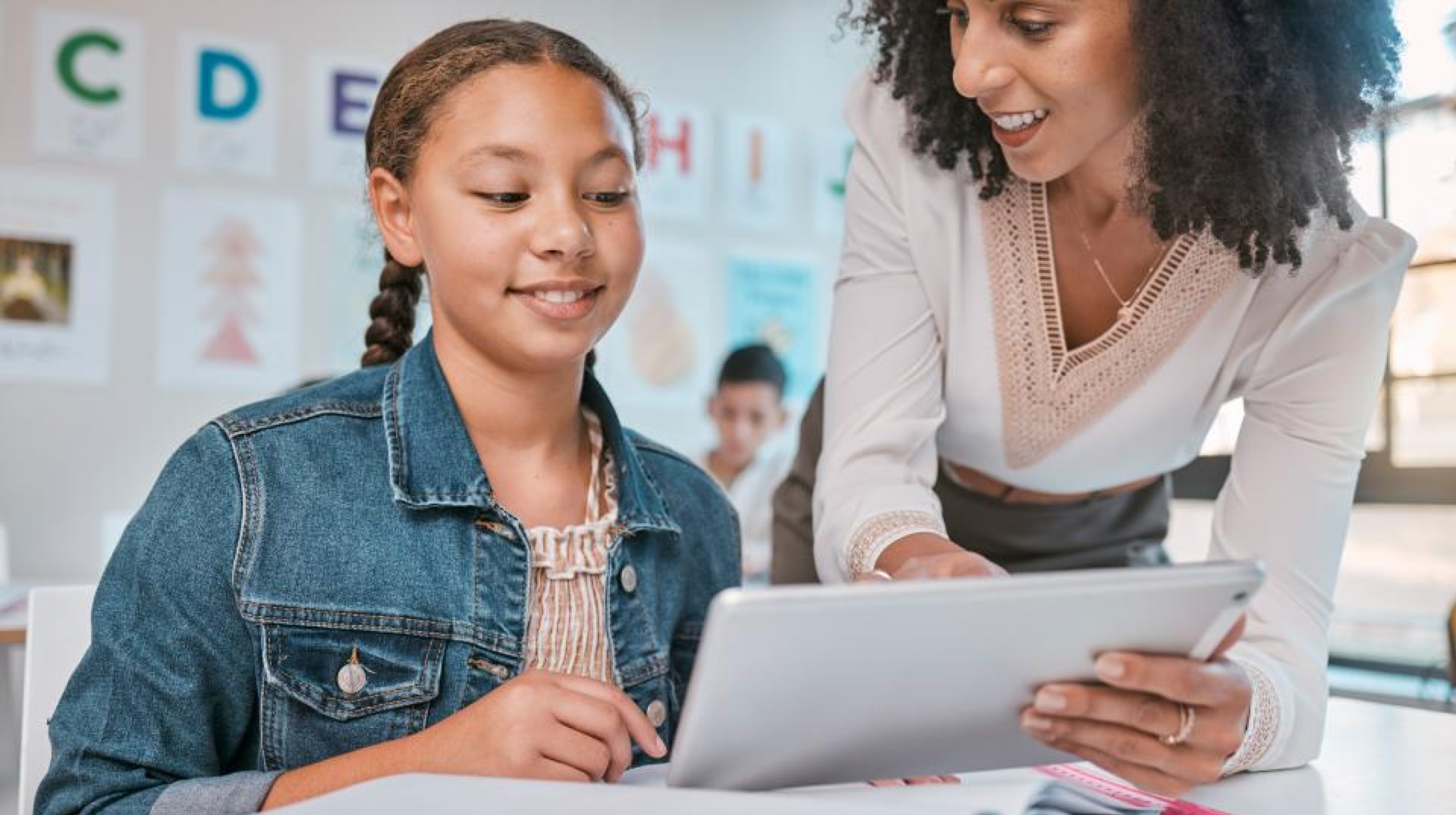 A photo of a student and teacher using a tablet representing AI in K–12 Education: The Good, the Bad, and the Guardrails to Consider