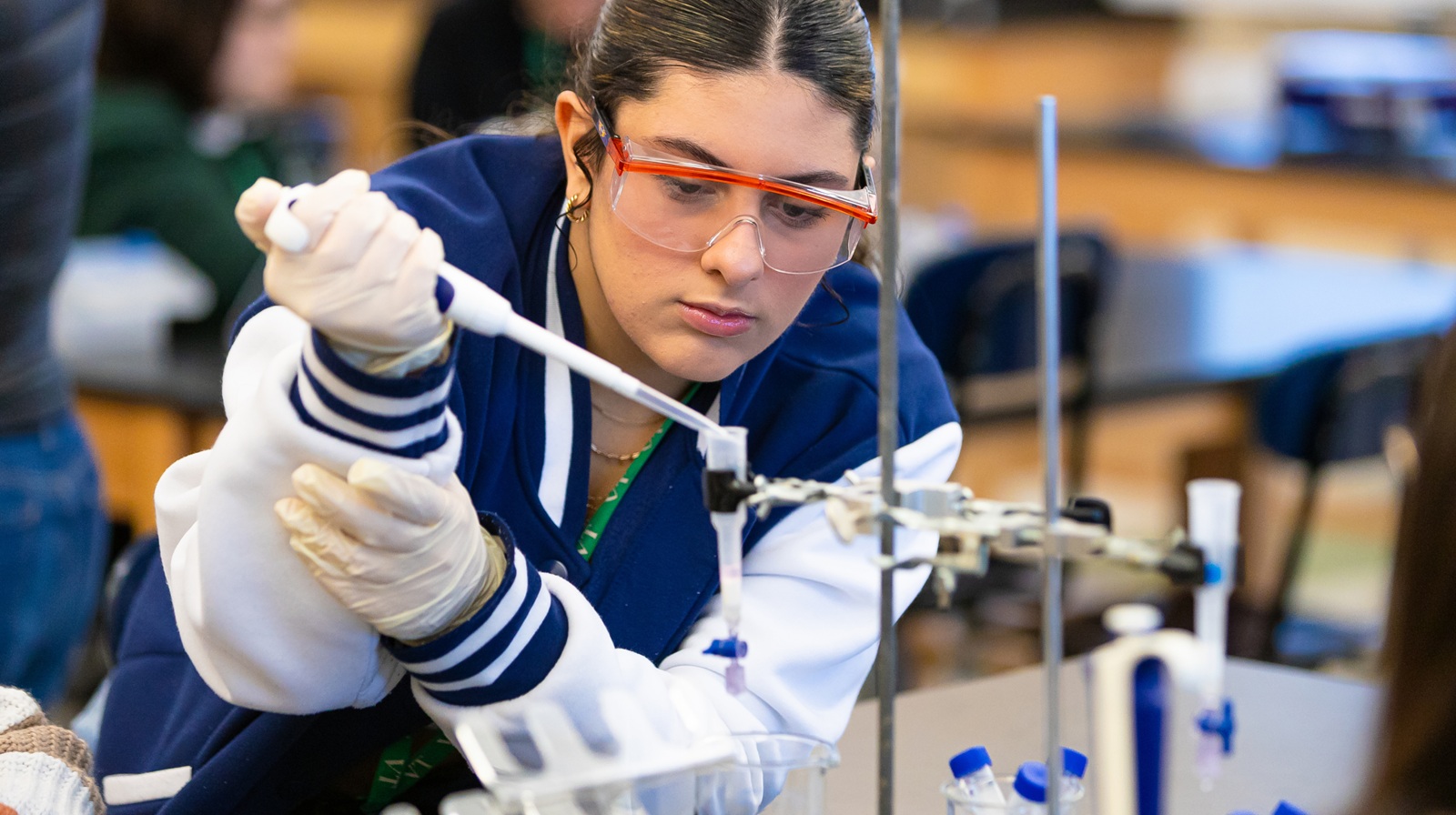 A high school student using a pipette to transfer liquid to a test tube in class.