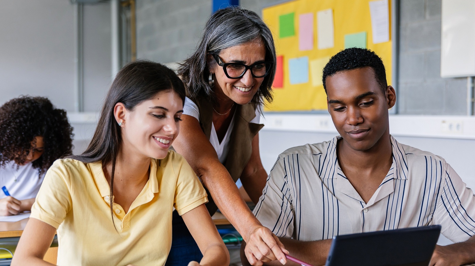 A photo of students and teacher using a computer representing 